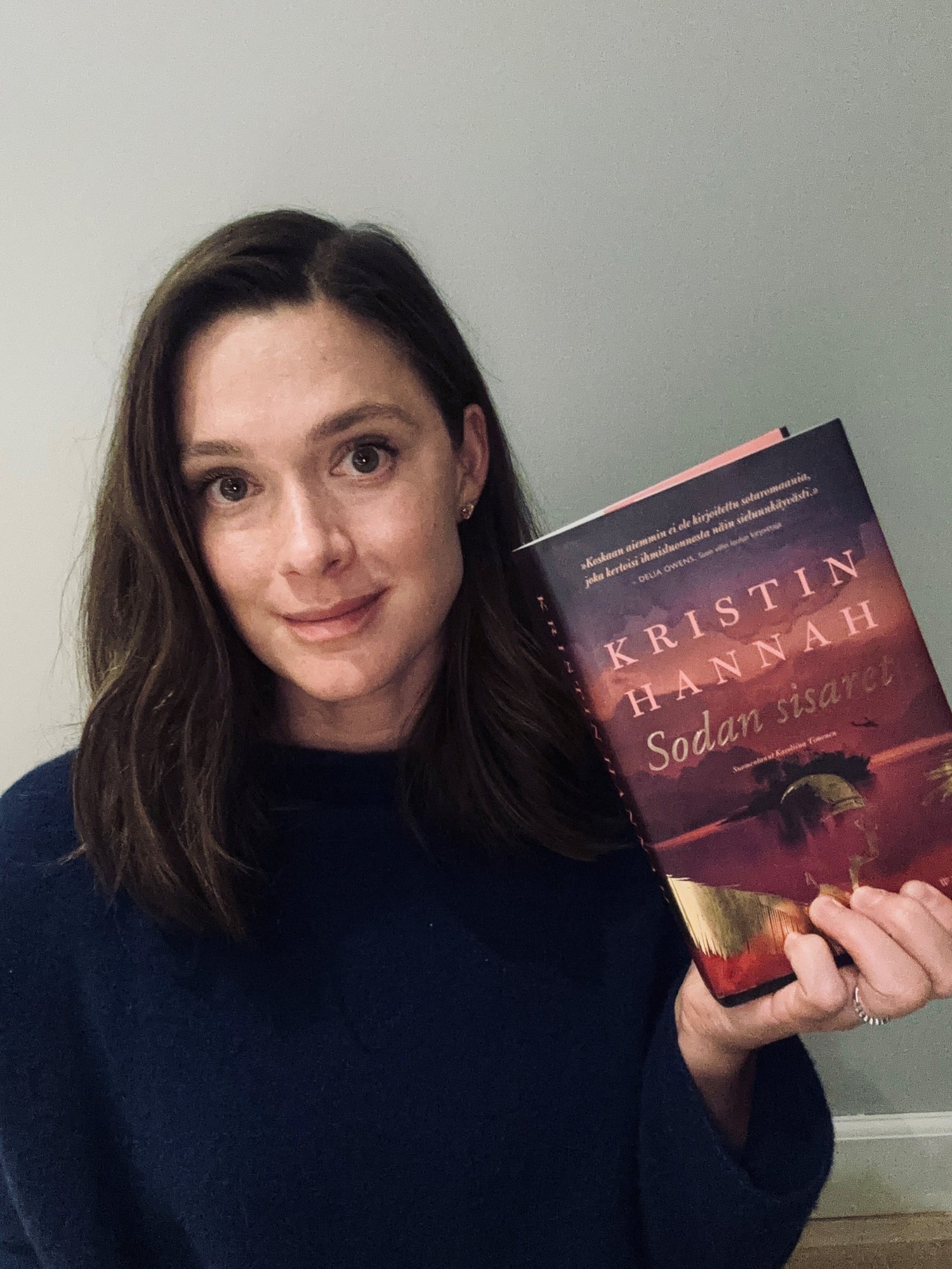 Puolikuva Krista Kososesta pitelemässä Kristin Hannahin Sodan sisaret -kirjaa.