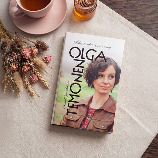 Kuvassa on Olga Temosen kirja Aika jonka sain vaalealla liinalla. Kirjan vieressä on kuppi teetä, hunajapurkki ja kuivakukkia.