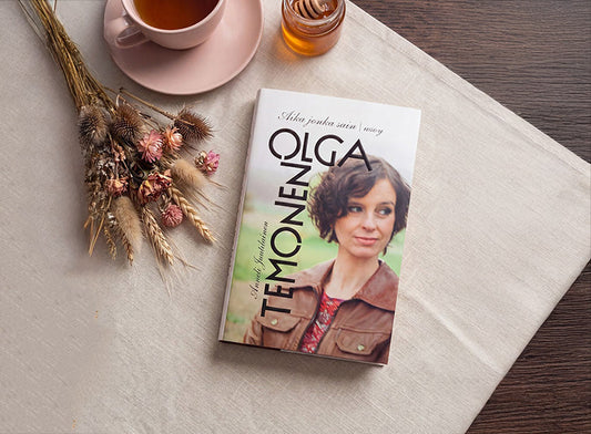 Kuvassa on Olga Temosen kirja Aika jonka sain vaalealla liinalla. Kirjan vieressä on kuppi teetä, hunajapurkki ja kuivakukkia.