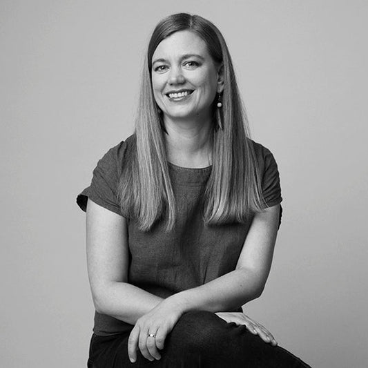 Mustavalkoinen puolikuva tuolilla istuvasta Anna Elina Isoarosta.