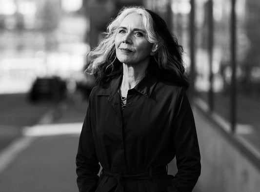 Mustavalkoinen muotokuva Anne Prokofjeffista kaupunkiympäristössä. Hänellä on pitkät vaaleat hiukset ja yllään tumma takki, ja hän kävelee kadulla kädet taskuissa. Tausta on sumentunut.