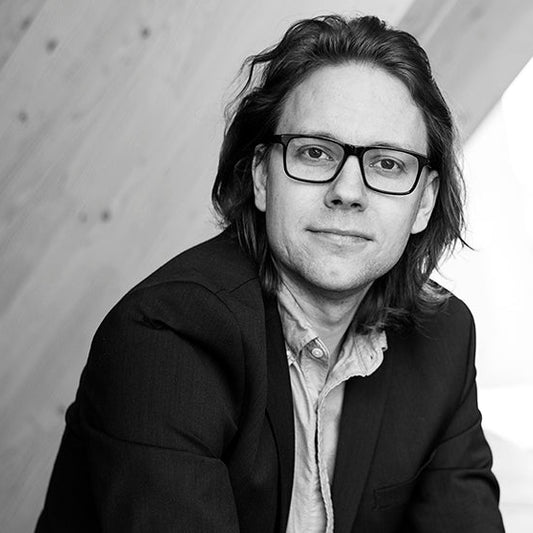 Kirjailija Esa Juntunen katsoo suoraan kameraan neutraalilla ilmeellä. Hänellä on päällään pikkutakki ja kauluspaita, ja hän käyttää silmälaseja. Kuva on mustavalkoinen, taustalla puupaneeliseinä ja kirkas ikkuna.