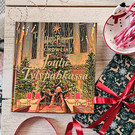 J.K. Rowlingin Jou­lu Ty­ly­pah­kas­sa -kirja jouluisella pöydällä