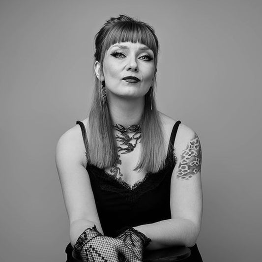 Kirjailija Laura Gustafsson istuu ja katsoo kameraan. Hänellä on hihaton toppi, näyttävä kaulakoru, verkkohansikas ja käsivarressa tatuointi. Hiukset ovat puolipitkät ja otsatukka suora. Mustavalkoinen kuva.