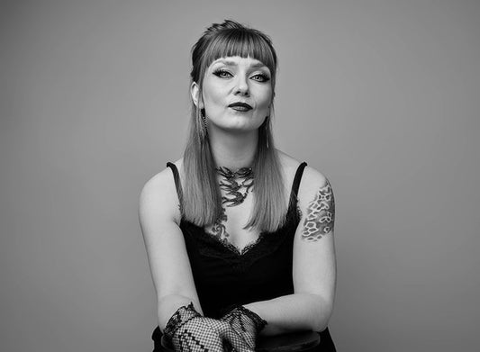 Kirjailija Laura Gustafsson istuu ja katsoo kameraan. Hänellä on hihaton toppi, näyttävä kaulakoru, verkkohansikas ja käsivarressa tatuointi. Hiukset ovat puolipitkät ja otsatukka suora. Mustavalkoinen kuva.